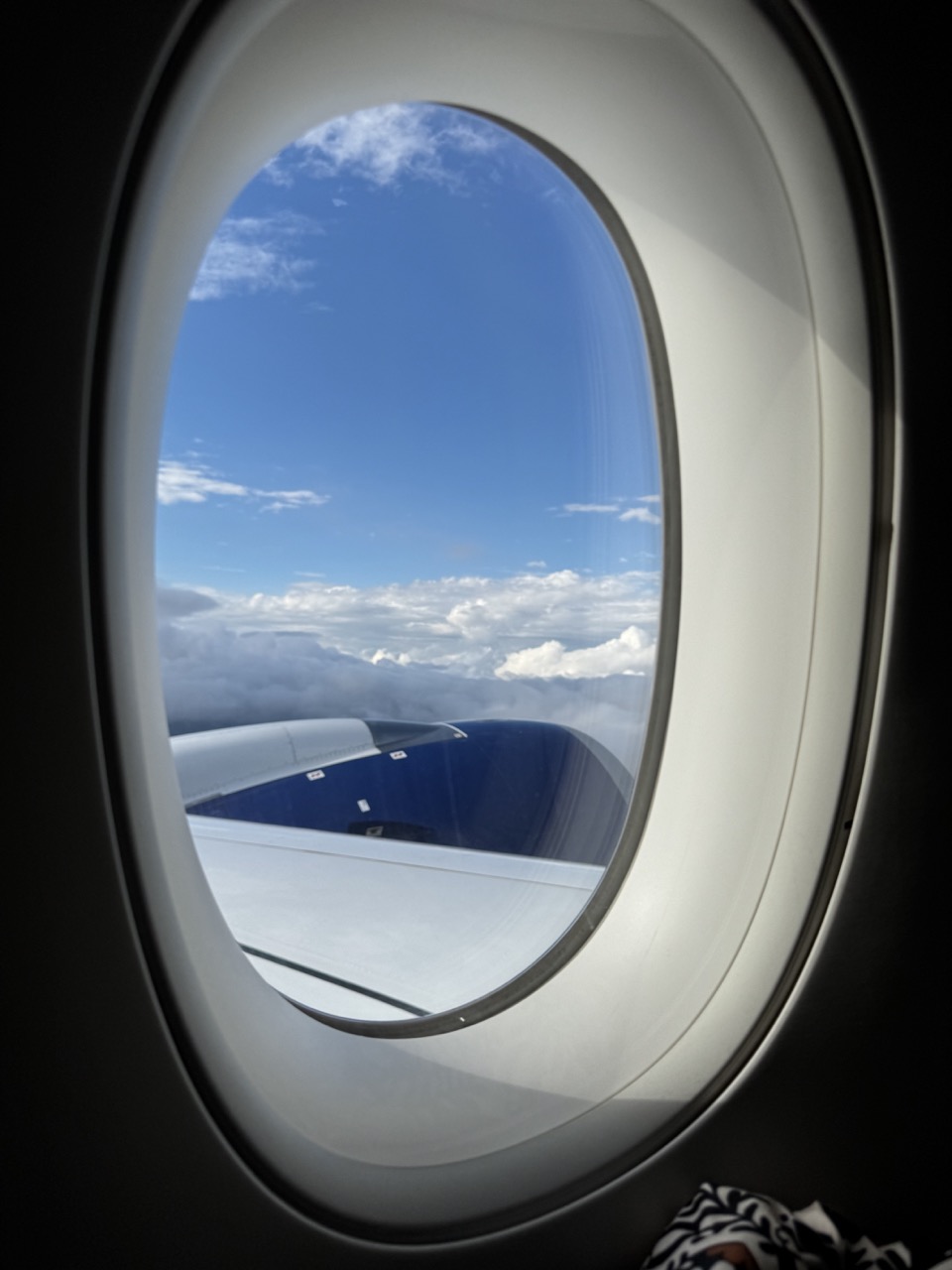 A spetacular view of the window of British Airways 246, a flight from São Paulo to London. The sky is bright with a couple of clouds. The wing of the plane is shining — this is a brand new aircraft.
